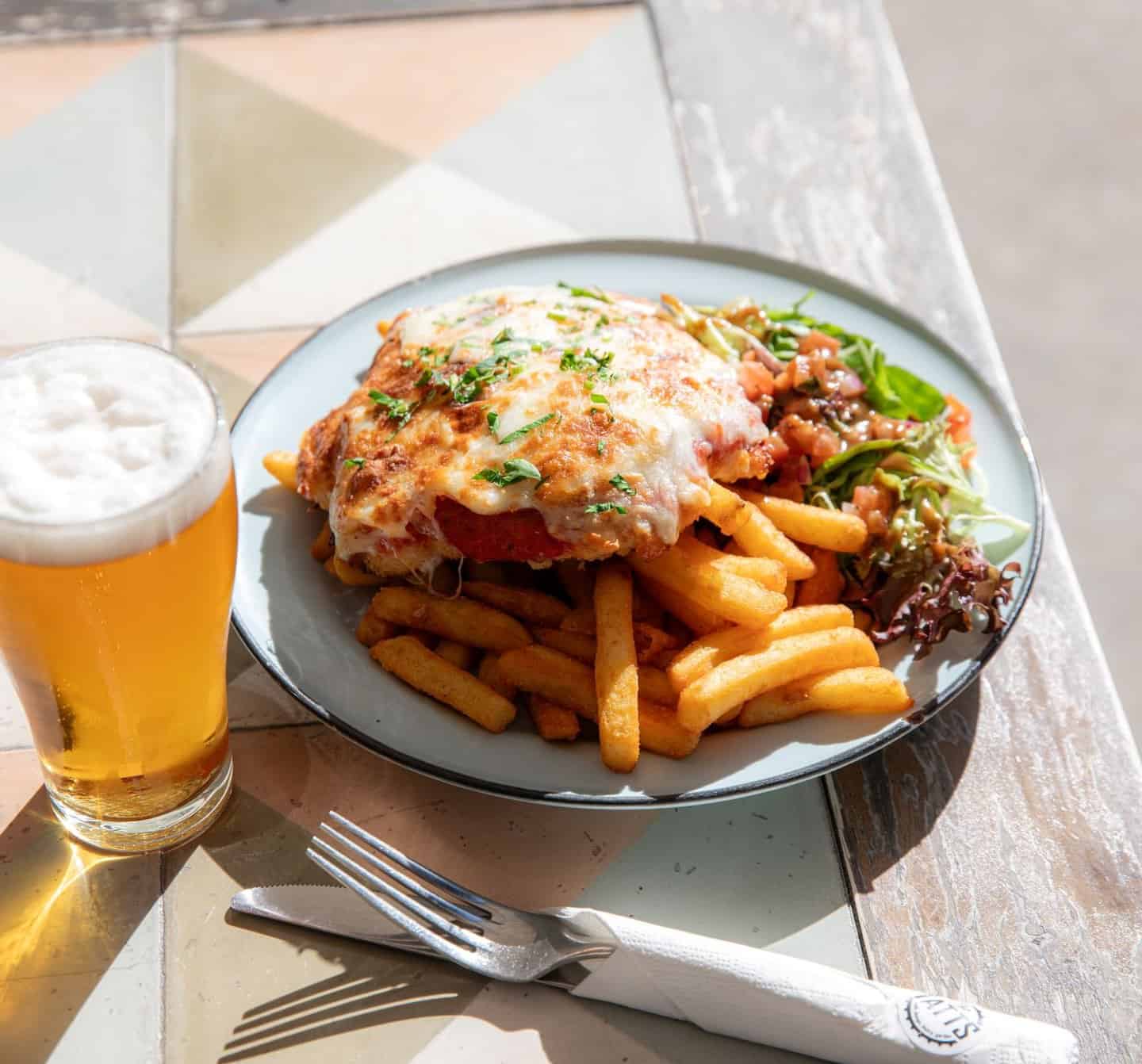 Chicken parmigiana with chips and a beer