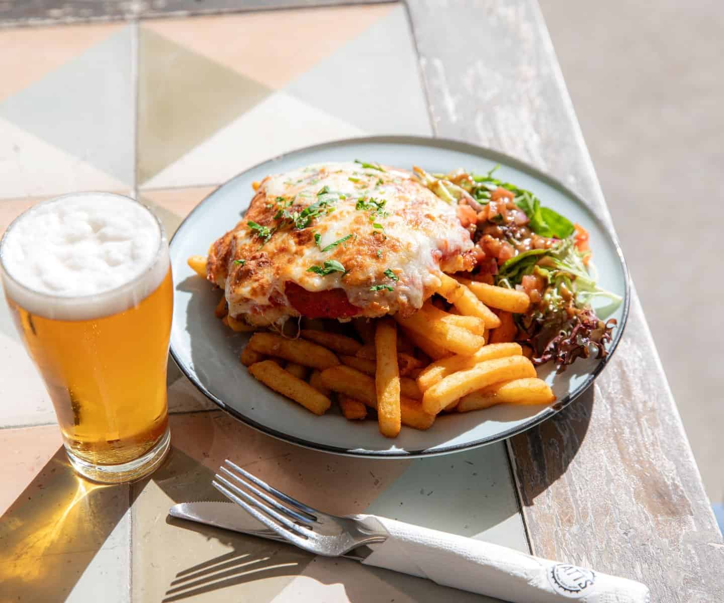 Chicken parmigiana with chips and a beer